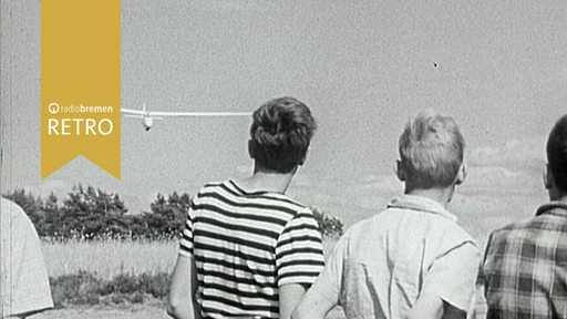 Ein paar Jungen beobachten, wie ein Segelflugzeug zur Landung ansetzt.