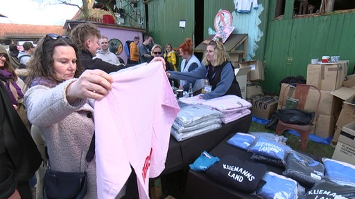 Eine Frau hält einen rosa Pullover hoch. Sie ist auf dem Flohmarkt im Kliemannsland.