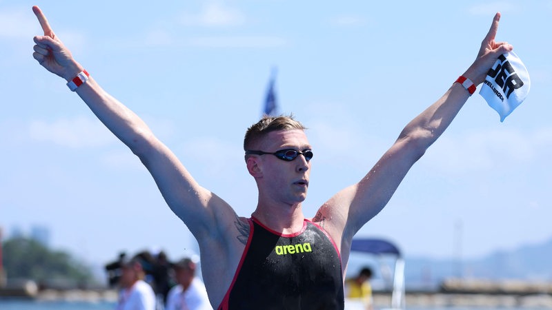 Florian Wellbrock streckt Hände in die Luft nach seinem WM-Gold in Japan, mit Schwimmbrille und in Sportkleidung