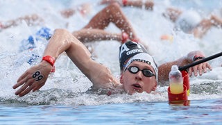 Florian Wellbrock krault bei der Schwimm-WM mit Badekappe und Taucherbrille, andere Schwimmer neben ihm
