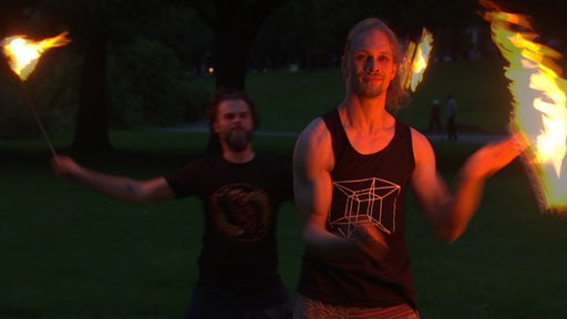 Zwei Männer jonglieren mit brennenden Fackeln am Osterdeich. 