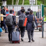 Eine Familie, vollbepackt mit Taschen und Koffern auf dem Weg durch einen Kontrollberreich.