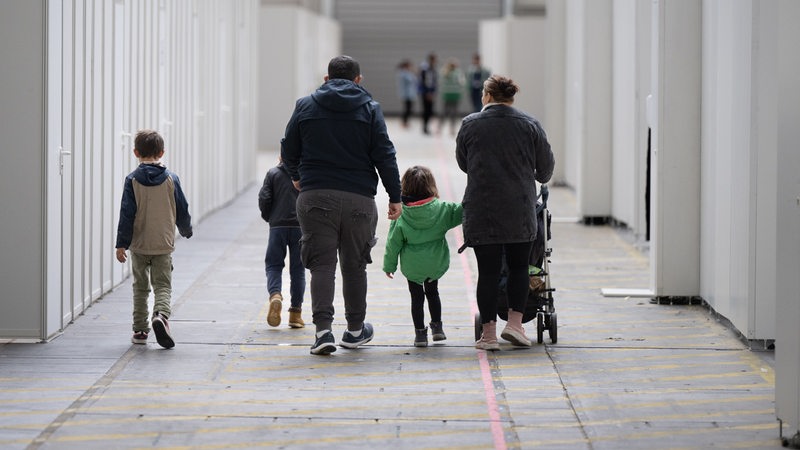 Eine Flüchtlingsfamilie geht durch die zu einer Massenunterkunft umfunktionierten Messehalle in Frankfurt. In der Halle sind seit einigen Wochen mehrere hundert Migranten und Asylsuchende aus unterschiedlichen Herkunftsländern untergebracht.
