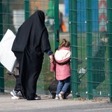 Eine Frau geht mit ihren Kinder durch einen Zauneingang (Archivbild)
