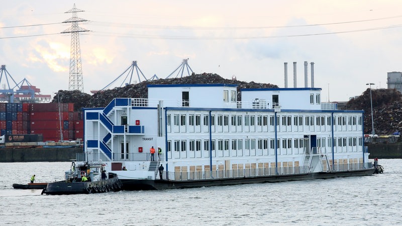 In Hamburg fährt ein Schiff mit Containern, in dem Flüchtlingen untergebracht wurden.