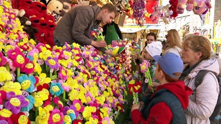 Ukrainische Flüchtlingskinder bekommen Kuscheltier-Blumen auf der Osterwiese an einem Stand geschenkt.