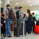 Reisende beim Check-In ihrer Koffer mit einer riesigen Warteschlange