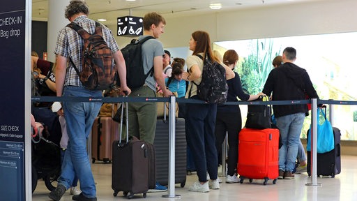 Reisende beim Checkin ihrer Koffer in einer Warteschlange Am Flughafen Bremen.