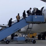 Zu sehen sind mehrere Fluechtlinge, die in ein Flugzeug einsteigen.