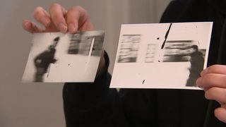Ein Jugendlicher hält zwei schwarz-weiß Fotos hoch, welche mit einer Analogakamera gemacht wurden.