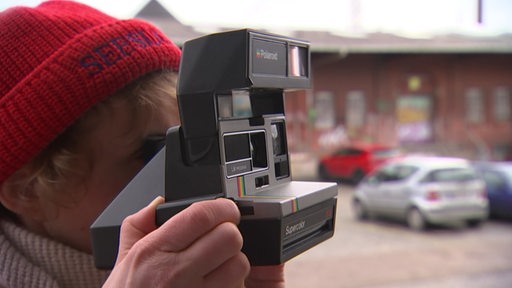 Eine Fotografin schießt ein Foto mit einer Polaroid-Kamera