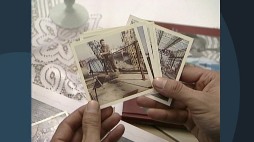 Eine Person hält mehrere alte Fotografien eines Mannes in einer Fabrikhalle in den Händen.