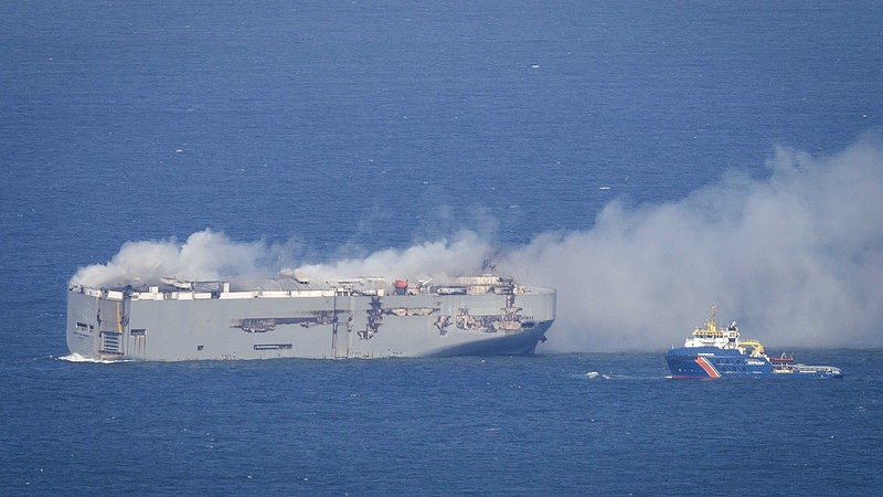 Rauch steigt von einem Frachter im Meer auf.