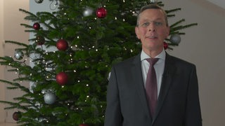 Bürgerschaftspräsident Frank Imhoff von der CDU steht vor einem Weihnachtsbaum.