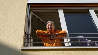 Eine Seniorin lehnt sich aus ihrem Zimmerfenster im Pflegeheim