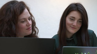 Zwei Frauen arbeiten an Laptops.