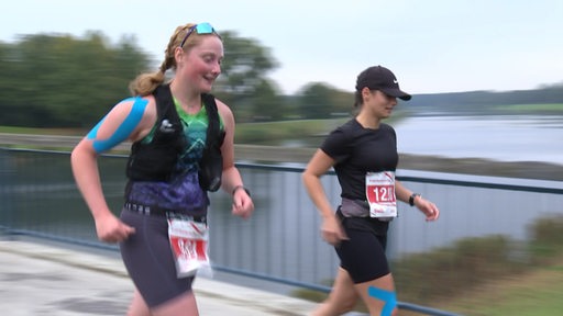 Zwei Läuferinnen auf einer Brücke.