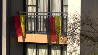 Zwei Deutschlandflaggen hängen von einem Balkon.