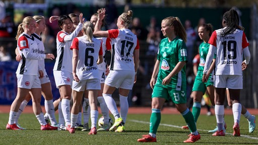 Werder Fußballerinnen schauen enttäuscht auf dem Spielfeld, während die Frankfurter Gegnerinnen ihren Treffer bejubeln.