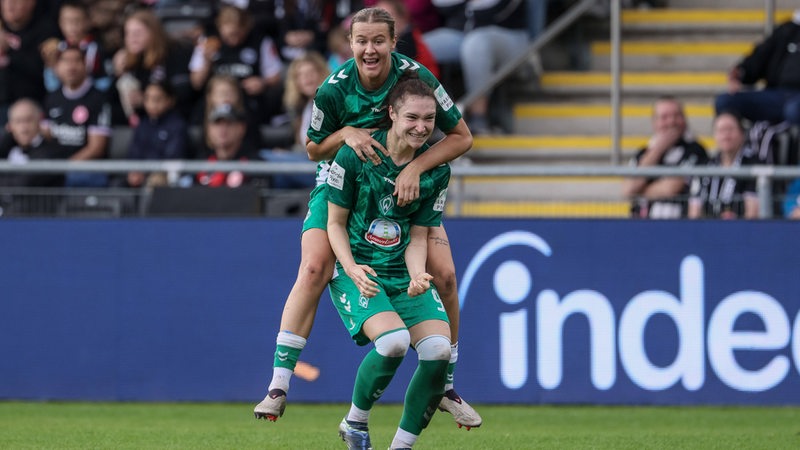 Werder-Fußballerin Larissa Mühlhaus springt freudig ihrer Mitspielerin Sophie Weidauer auf den Rücken, die gerade ein furioses Tor gegen Frankfurt geschossen hat.