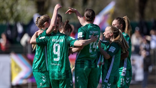 Die Fußballerinnen von Werder Bremen kommen auf dem Spielfeld zusammen und bejubeln ein Tor.