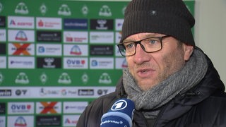 Werders Frauen-Fußballtrainer Thomas Horsch mit einer schwarzen Wollmütze auf dem Kopf beim TV-Interview nach dem Spiel.