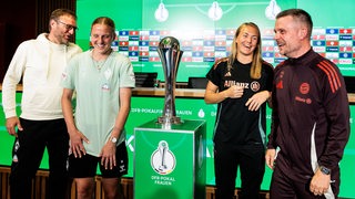 Werder-Trainer Thomas Horsch und Kapitänin Lina Hausicke stehen lachend nach der Pressekonferenz neben dem DFB-Pokal und scherzen mit Bayern-Spielerin Magdalena Eriksson und Trainer Alexander Straus.