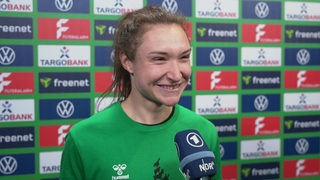 Werders Doppeltorschützin Sophie Weidauer steht mit breitem Strahlen vor einer Werbewand beim Interview nach dem Einzug ins Pokal-Finale.