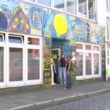 Drei Frauen stehen vor einem bunt bemalten Gebäude