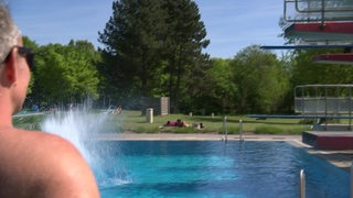 Ein Besucher schaut auf den Sprungturm im Freibad.