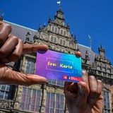 Eine Hand hält die Freikarte demonstrativ in die Kamera