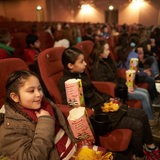 Kinder sitzen mit Popcorn-Tüten im Kino (Symbolbild)