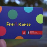 Im Vordergrund ist die Freikarte und im Hintergrund ein verschwommenes Gebäude zu sehen.