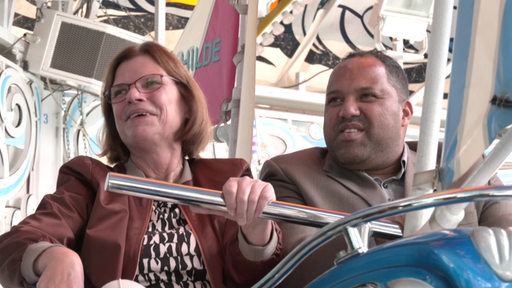 Die Wirtschaftssenatorin Kristina Vogt und Ailton in einem Fahrgeschäft auf dem freimarkt 2022.