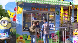 Zwei Jungs stehen an der Kasse eines Freimarkt-Karussells.