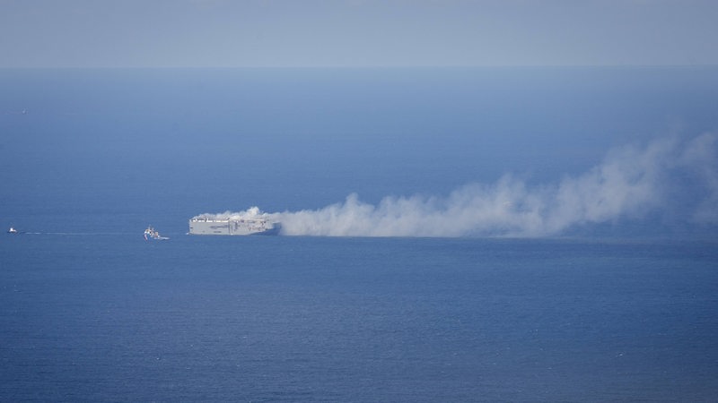 Eine Rauchwolke steigt von einem großen Frachter auf dem Meer auf.