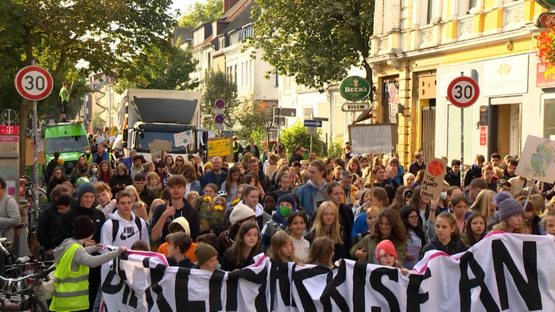 Zahlreiche Menschen tragen Banner und Plakate und ziehen auf einer Demonstration von Fridays for Future durch Bremen.