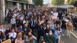 Junge Leute stehen in Bremen auf einer Straße und halten Plakate und Schilder in die Höhe. Auf den stehen Botschaften wie: "Das ist unsere Welt!" Die Menschen nehmen am Klimastreik von Fridays for Future teil.