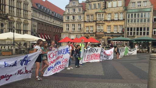 Rund 30 junge Menschen stehen mit Transparenten auf dem Marktplatz in Bremen.