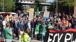 Menschen in einer Gruppe tragen Fahnen und Plakate.