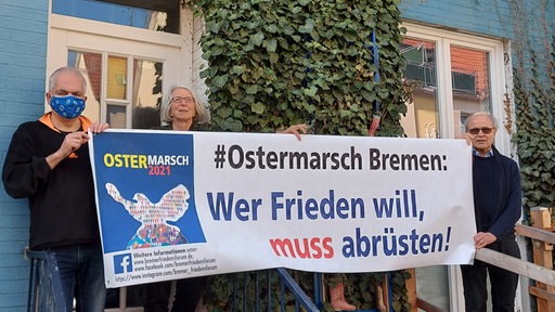 Menschen mit einem Plakat auf dem steht: "#Ostermarsch Bremen: Wer Frieden will, muss abrüsten."