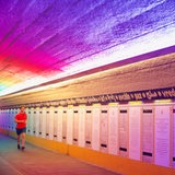 Jogger vor bunt ausgeleuchteten Texttafeln in einem Tunnel