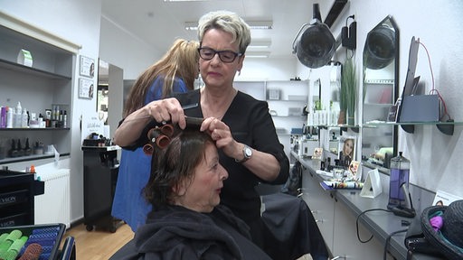 Die Friseurin Susi Kruse wickelt einer Frau die Locken.