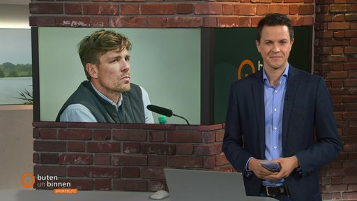 Yannick Lowin moderiert im Sportblitz-Studio einen Beitrag zu Clemens Fritz an, er ist im Hintergrund auf dem Bildschirm zu sehen.