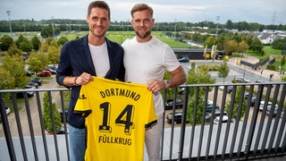Niclas Füllkrug hält zusammen mit Sebastian Kehl sein Dortmund Trikot in der Hand