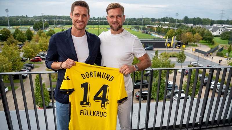 Niclas Füllkrug hält zusammen mit Sebastian Kehl sein Dortmund Trikot in der Hand