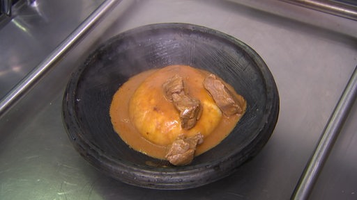 Fufu mit Erdnusssauce, angerichtet auf einem grauen Teller.
