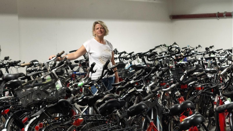 Eine Frau steht in einem Keller zwischen Fahrrädern.