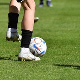 Nahe Ansicht von Beinen eines Spielers, der einen Fußball kickt.