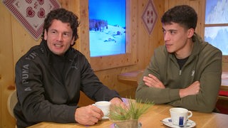 Die Werder Fußballspieler Nelson Valdez und Julian Malatini sitzen bei einem Kaffee in einer Almhütte.